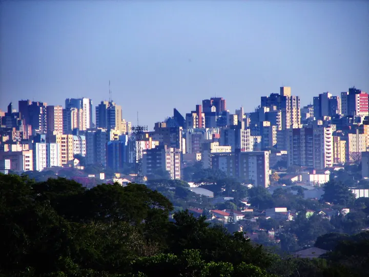 Edifícios de Londrina vistos entre árvores durante o dia; fotografia de contexto, sem representação da UEL ou de hospital