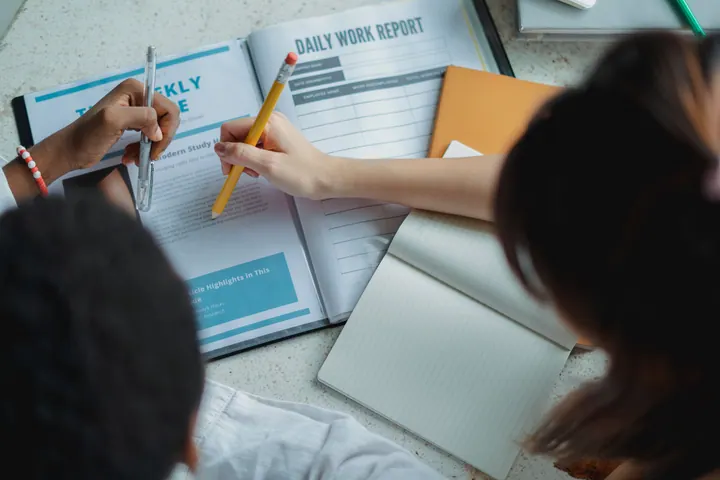 Mãos sobre relatórios, caderno e materiais de organização de estudo