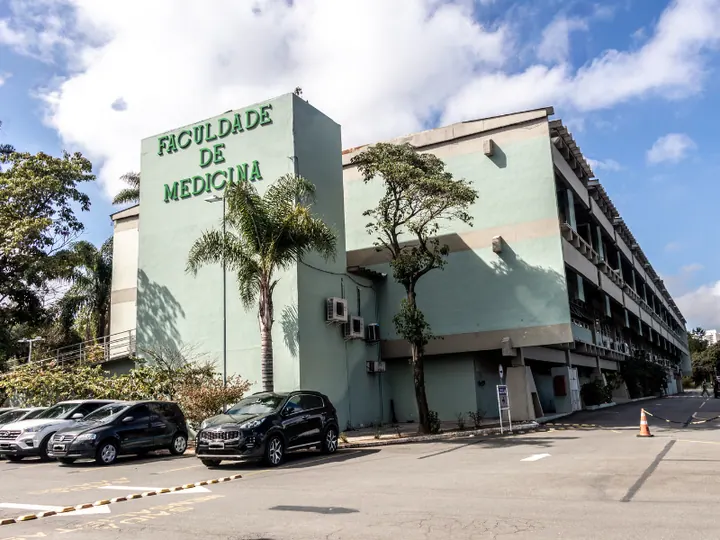 Fachada verde do prédio da Faculdade de Medicina do ABC, com identificação da faculdade, árvores e estacionamento à frente