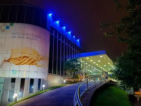 Fachada e rampa de entrada do Hospital São Lucas em Ribeirão Preto, iluminadas de azul à noite.
