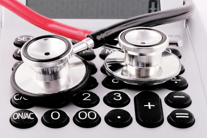 Estetoscópios sobre uma calculadora, em fotografia de planejamento financeiro na medicina