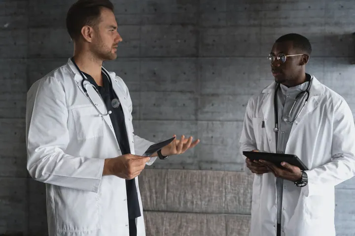 Dois profissionais de medicina discutindo informações em tablets