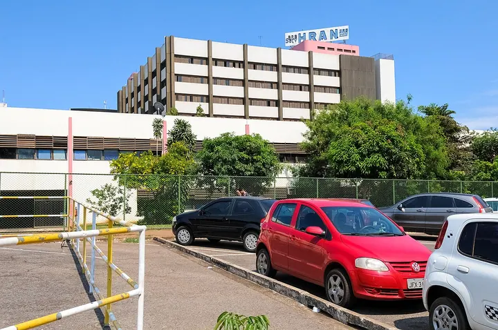 Fachada do Hospital Regional da Asa Norte com a identificação HRAN no topo, jardim e estacionamento em primeiro plano.