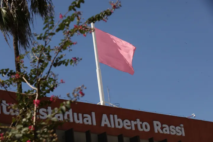 Identificação do Hospital Estadual Alberto Rassi na fachada, sob uma bandeira rosa da campanha Outubro Rosa.