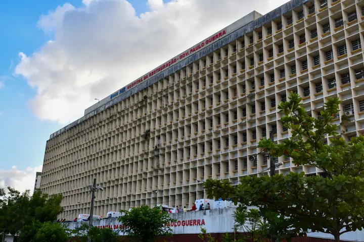 Fachada do Hospital da Restauração, no Recife, com identificação da unidade, árvores e ambulâncias.